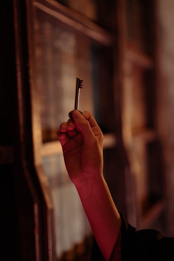 pexels-photo-8391462 A hand holding an antique key is seen in a dimly lit room, evoking mystery and intrigue.